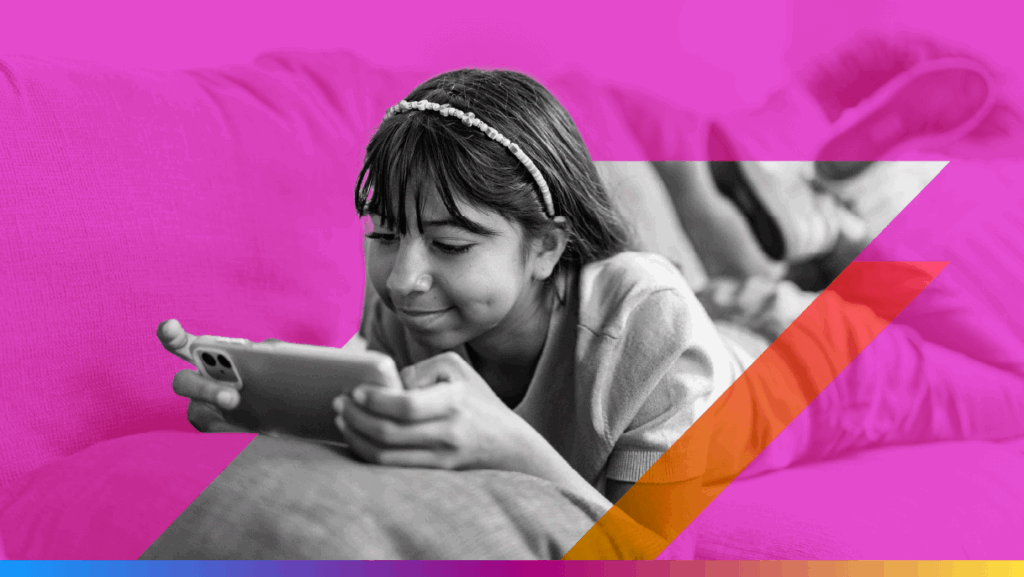 a generation alpha kid lies on a couch, playing on a phone - featured image for gen alpha retail trends article